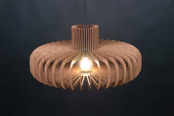 Disc wooden pendant light in walnut – wide ring of curved slats, lit with a warm glow, dark background